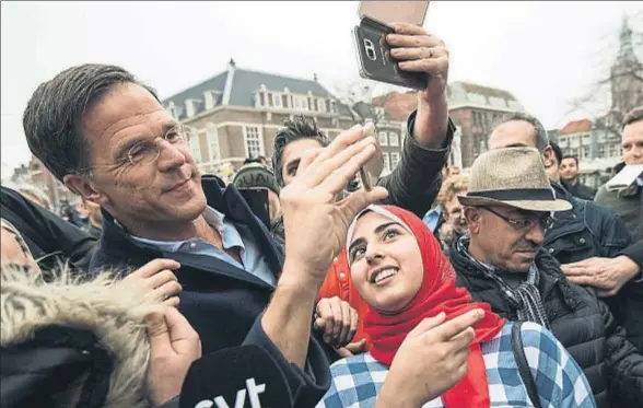  ?? CARL COURT / GETTY ?? El primer ministro holandés, Mark Rutte, haciéndose una foto con algunos seguidores durante una visita de campaña, ayer en La Haya