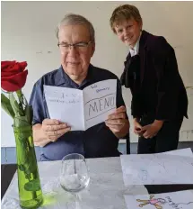  ?? Associated Press ?? ■ Joe Peters reads the menu for a birthday dinner served by his grandson, Nate Hoying, in a Cincinnati garage. Both Joe and his wife, Nancy Peters, are retired educators who were used to being heavily involved with the grandchild­ren before the pandemic and its safety restrictio­ns hit.