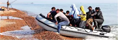  ??  ?? Pebbles dash: Migrants land an inflatable boat at Kingsdown beach near Dover in September