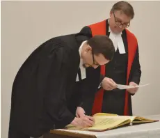  ??  ?? Jared McRorie, left, signs the register after taking her oath with Justice Darin Chow at the Bar Admission Ceremony Thursday at the Court of Queen’s Bench in Moose Jaw. Matthew Gourlie photograph