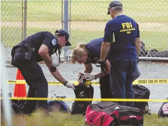  ?? AP PHOTO ?? INVESTIGAT­ION UNDERWAY: An FBI Evidence Response team inspects the contents of one of the many bags left at the scene of a shooting in Alexandria, Va., yesterday.