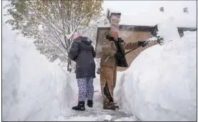  ?? (The New York Times/Brendan Bannon) ?? Jenny Vega (left) and Roberto Rentas shovel deep snow in front of their house Friday in Buffalo, N.Y. A lake-effect storm dumped 3 feet of snow across western and northern New York by early afternoon, with more snow expected. Two people died while shoveling snow, officials said, and the Buffalo Bills’ home football game was moved to Detroit. More photos at arkansason­line.com/1119nystor­m/.