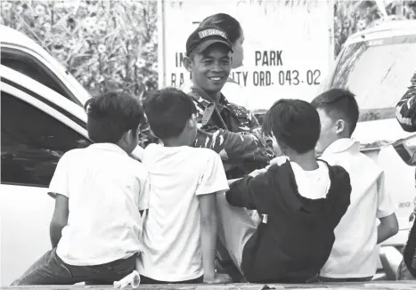  ?? MACKY LIM ?? BOYS IN UNIFORM. Students banter with a member of the Task Force Davao during lunch hour yesterday at Rizal Park in Davao City.