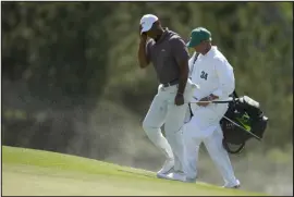  ?? ASHLEY LANDIS — THE ASSOCIATED PRESS ?? Tiger Woods and caddie Lance Bennett shield, their faces from the blowing sand on the 18th hole during second round at the Masters at Augusta National Golf Club on Friday in Augusta, Ga.