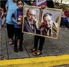  ?? THE NEW YORK TIMES ?? A woman holds a portrait of brothers Fidel and Raul Castro as a caravan carrying Fidel’s ashes passes in Santa Clara, Cuba, on Dec. 1, 2016. Raul Castro resigned Friday as head of Cuba’s Communist Party.