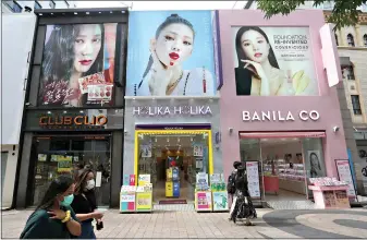  ?? (AP Photo/Ahn Young-joon) ?? People pass by cosmetics shops July 3 on a shopping street in Seoul, South Korea. In the wake of mass protests against racial injustice in the U.S., corporatio­ns are re-branding their skin lightening products in Africa, Asia and the Middle East, but for generation­s of women raised on their messaging, the new marketing is unlikely to reverse deeply rooted prejudices around colorism, the idea that fair skin is better than dark skin.