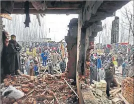  ?? AFP ?? Onlookers gather outside a damaged house after a gunfight between militants and security forces at Mujgund area, on the outskirts of Srinagar on Sunday.