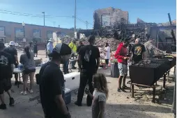  ?? THE ASSOCIATED PRESS ?? Volunteers prepare hamburgers for painting volunteers working in front of one of the dozens of burnt buildings in Kenosha, Wisconsin, on Sunday as the city remained on edge following the police shooting of Jacob Blake, a Black man, and the violent protests that followed.