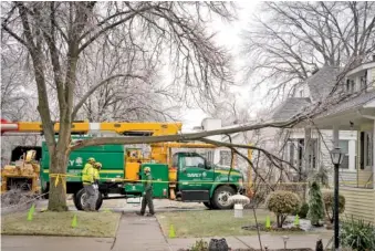  ?? MANDI WRIGHT/DETROIT FREE PRESS VIA AP ?? On Thursday, a crew from Davey Tree cuts a large branch away from a home and sidewalk on Woodward Heights in Pleasant Ridge, Mich.