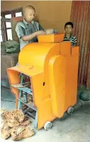 ??  ?? Semi-automatic coconut de-husking machine with Samarasing­he Bandara – investor of the machine - feeding coconut into the machine assisted by one of his sons.