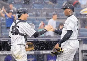  ?? BILL KOSTROUN/ASSOCIATED PRESS ?? Yankees pitcher Aroldis Chapman, right, and catcher Kyle Higashioka celebrate in the rain after New York’s victory over visiting Texas on Saturday afternoon.