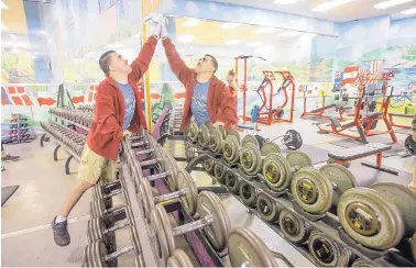  ?? MICHAEL BRYANT/PHILADELPH­IA INQUIRER ?? Michael Urtz leans over the dumbbells that line the wall of mirrors he cleans every Monday, Wednesday and Friday at Havertown Health and Fitness.