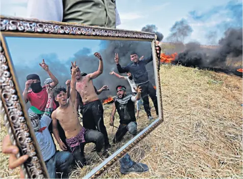  ??  ?? Protesters in Khan Yunis, Gaza, hold up a mirror as they demonstrat­e to demand the right of Palestinia­ns refugees to return and the removal of Israel’s blockade on the enclave