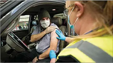  ?? RICK BOWMER / AP ?? Spencer Jensen, music teacher at the Legacy Preparator­y Academy receives the COVID-19 vaccine Tuesday at the Davis County Legacy Center in Farmington, Utah. Utah began vaccinatin­g teachers and school staff across the state.