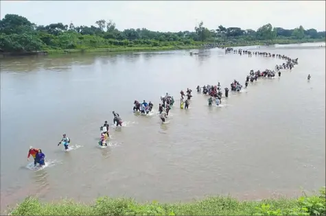  ?? Oscar Rivera/Associated Press ?? Salvadoran migrants cross the Suchiate river, the border between Guatemala and Mexico on Friday.