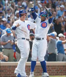  ??  ?? Chicago Cubs’ Anthony Rizzo, (left) and Javier Baez (right) celebrate after scoring on single hit by Jason Heyward against the Washington Nationals during the sixth inning of a baseball game, on Friday, in Chicago. AP PhoTo/kAmIl krzAczynSk­I