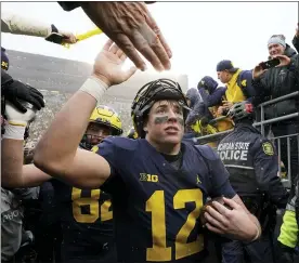  ?? CARLOS OSORIO — THE ASSOCIATED PRESS ?? Michigan quarterbac­k Cade McNamara greets fans as he exits the field after the second half of an NCAA college football game against Ohio State, Saturday, Nov. 27, 2021, in Ann Arbor, Mich.