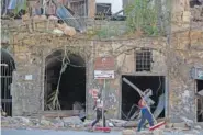  ?? AP PHOTO/FELIPE DANA ?? Women with brooms pass by a historic building damaged by Tuesday’s explosion in the Gemmayzeh neighborho­od of Beirut, Lebanon, on Saturday.