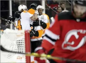  ?? JULIO CORTEZ — THE ASSOCIATED PRESS ?? Philadelph­ia Flyers center Sean Couturier, top left, celebrates with teammates center Jordan Weal, center, right wing Wayne Simmonds (17) after scoring a goal against the New Jersey Devils during the first period Saturday.