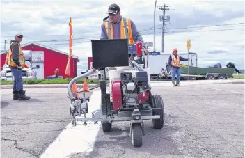  ?? ALISON JENKINS/JOURNAL PIONEER ?? The City of Summerside has a four-person crew dedicated to painting road markings from May to November. Robert McFeely, centre, runs the city’s painting machine while William Noye, left, and Sandy Wedge flag the intersecti­on of Queen Street and Heather Moyse Drive in Summerside June 4.