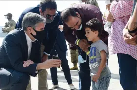  ?? (AP/Olivier Douliery) ?? Secretary of State Antony Blinken shows a picture of his children to a young Afghan refugee Wednesday outside a hangar used for evacuation operations at Ramstein Air Base in Germany.