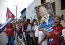  ?? — AP ?? BAIRES: A woman holds a portrait of Fidel Castro after his ashes passed through the eastern Cuba town.