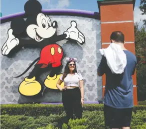  ?? OCTAVIO JONES / GETTY IMAGES ?? Michael Callahan takes a photo of his friend Sarah Breland near the Walt Disney World
theme park entrance in Florida Thursday. The park is scheduled to reopen Saturday.