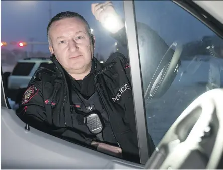  ?? PHOTOS: BRYAN PASSIFIUME ?? District 5 community resource officer Const. Colin Thorne peeks inside an idling vehicle during Operation Cold Start on Tuesday. Spearheade­d by Thorne, the program seeks out and educates drivers who leave their vehicles vulnerable to thieves.