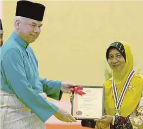  ?? PIC BY MUHAIZAN YAHYA ?? Sultan of Perak Sultan Nazrin Muizzuddin Shah presenting the Tokoh Guru award to Rahimah Mohd Sura in Kuala Kangsar yesterday.