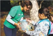  ??  ?? Instructor Elizabeth Geurts, left, shows the earth’s water content to fourth-grader Marissa Juarez.