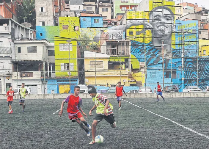  ??  ?? Kids play football in the Jardim Peri neighbourh­ood where Gabriel Jesus is featured in a mural.