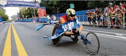  ?? CURTIS COMPTON / CCOMPTON@AJC.COM ?? Daniel Romanchuk, 18, crosses the finish line to win the men’s wheelchair race in the 48th AJC Peachtree Road Race. Romanchuk, who won the Junior Peachtree last year, had an unofficial time of 20 minutes, 2 seconds.