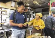  ?? ASSOCIATED PRESS ?? Former rugby player Toetu’u Taufa and Harumi Okuno, co-owner of a Takoyaki stand, sort through paper fans near Hanazono Stadium.