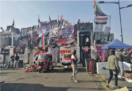  ?? AP ?? Protesters sit on barriers set up by the Iraqi security forces to close a bridge leading to the Green Zone in Baghdad