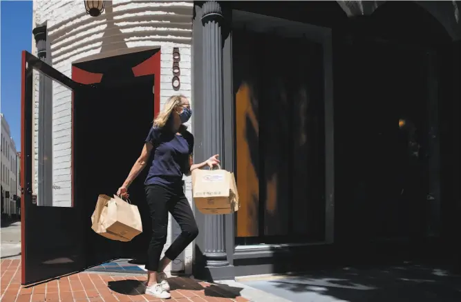  ?? Santiago Mejia / The Chronicle ?? Jennifer Sherman of the restaurant­s Quince and Cotogna carries meal bags for the project feeding idled Bay Area music industry workers.