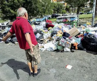  ?? (foto Percossi/Ansa) ?? Primavalle Uno sconsolato cittadino allarga le braccia a largo di Santa Teresa Verzeri vedendo la montagna di rifiuti
