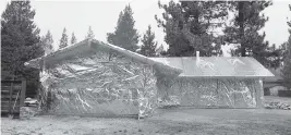  ?? JAE C. HONG AP ?? Martin Diky’s home completely wrapped in fire-resistant material to protect the property against the approachin­g Caldor Fire in Meyers, Calif. Diky decided to order $6,000 worth of aluminum protective covering to wrap his home near Lake Tahoe in June as the last big wildfire roared through the Sierra dozens of miles southwest of the forested alpine waters.