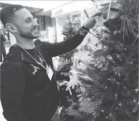  ?? DAN JANISSE ?? Volunteer Leo Arakelian hangs a star on one of five trees at Devonshire Mall on Tuesday to help launch the fourth annual Light the Way campaign, which raises funds for the local branch of the Canadian Mental Health Associatio­n.