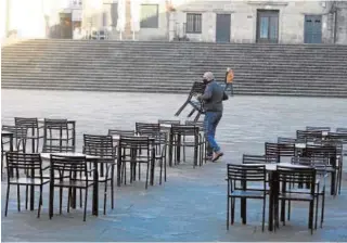  ?? MIGUEL MUÑIZ ?? Un hostelero retira el mobiliario de la terraza de su local