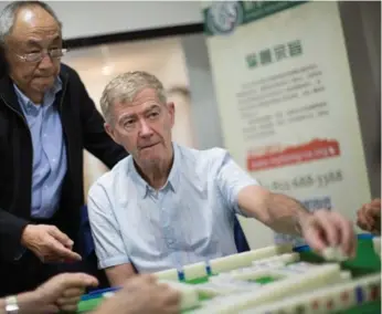  ?? NICK KOZAK FOR THE TORONTO STAR ?? Ying Fu Wang of the Canada Mahjong Associatio­n helps Brian Lansdowne play at the group’s weekly workshop.