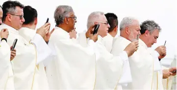  ??  ?? Clergy members use mobile phones as Pope Francis arrives to leads a holy mass at Enrique Olaya Herrera airport in Medellin, Colombia. — Reuters photo