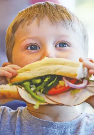  ?? STAFF PHOTOS BY ERIN O. SMITH ?? Owen Culberson, 4, takes a bite out of a Subway sandwich he made in a nutrition class focused on choosing colorful foods.