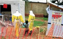  ?? AP ?? Health workers walk with a boy suspected of having the Ebola virus at an Ebola treatment centre in Beni, Eastern Congo.