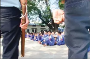  ?? HENG CHIVOAN ?? Prisoners sit in the courtyard of Phnom Penh’s Prey Sar prison under the watch of guards in 2009.