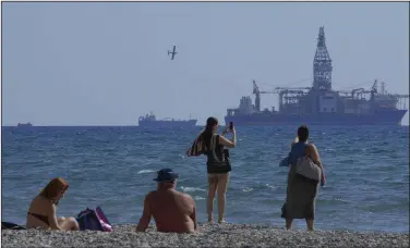  ?? (AP/Petros Karadjias) ?? People on the beach take photos of the “Tungsten Explorer” drilling ship, in the southern coastal city of Larnaca, Cyprus, in late 2021.