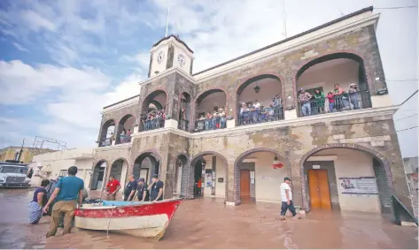  ??  ?? Habitantes de Tecuala, Nayarit, utilizan una lancha para rescatar a personas y llevarlas a la presidenci­a municipal; policías estatales ayudan en las labores.