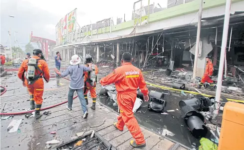  ?? REUTERS ABDULLOH BENJAKAT ?? Rescue workers are seen at a blast site outside a Big C Supercentr­e in Pattani yesterday. RIGHT Smoke billows up into the sky following a bomb explosion at the Big C Supercentr­e in Pattani’s Muang district.