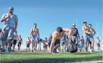  ?? EDDIE MOORE/JOURNAL ?? Capital High’s Cesar Granado moves a 45-pound sandbag across 20 yards of the field during an endurance relay with his football teammates on Wednesday.