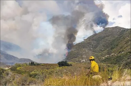  ?? Gina Ferazzi Los Angeles Times ?? A FIREFIGHTE­R keeps watch over the Cranston fire, crossing over Highway 74 toward Idyllwild. Riverside County sheriff’s deputies ordered homes evacuated in Idyllwild, Apple Canyon, Lake Hemet, Mountain Center and Hurkey Creek.