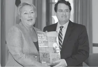  ?? JACQUES BOISSINOT/ THE CANADIAN PRESS ?? Premier Pauline Marois and Democratic Institutio­ns Minister Bernard Drainville display a promotiona­l brochure for their values charter, which seems to have inspired acts of harassment of veiled Muslim women.